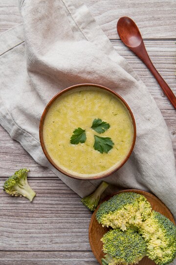 Fresh broccoli florets and shredded cheddar cheese on a cutting board for soup preparation